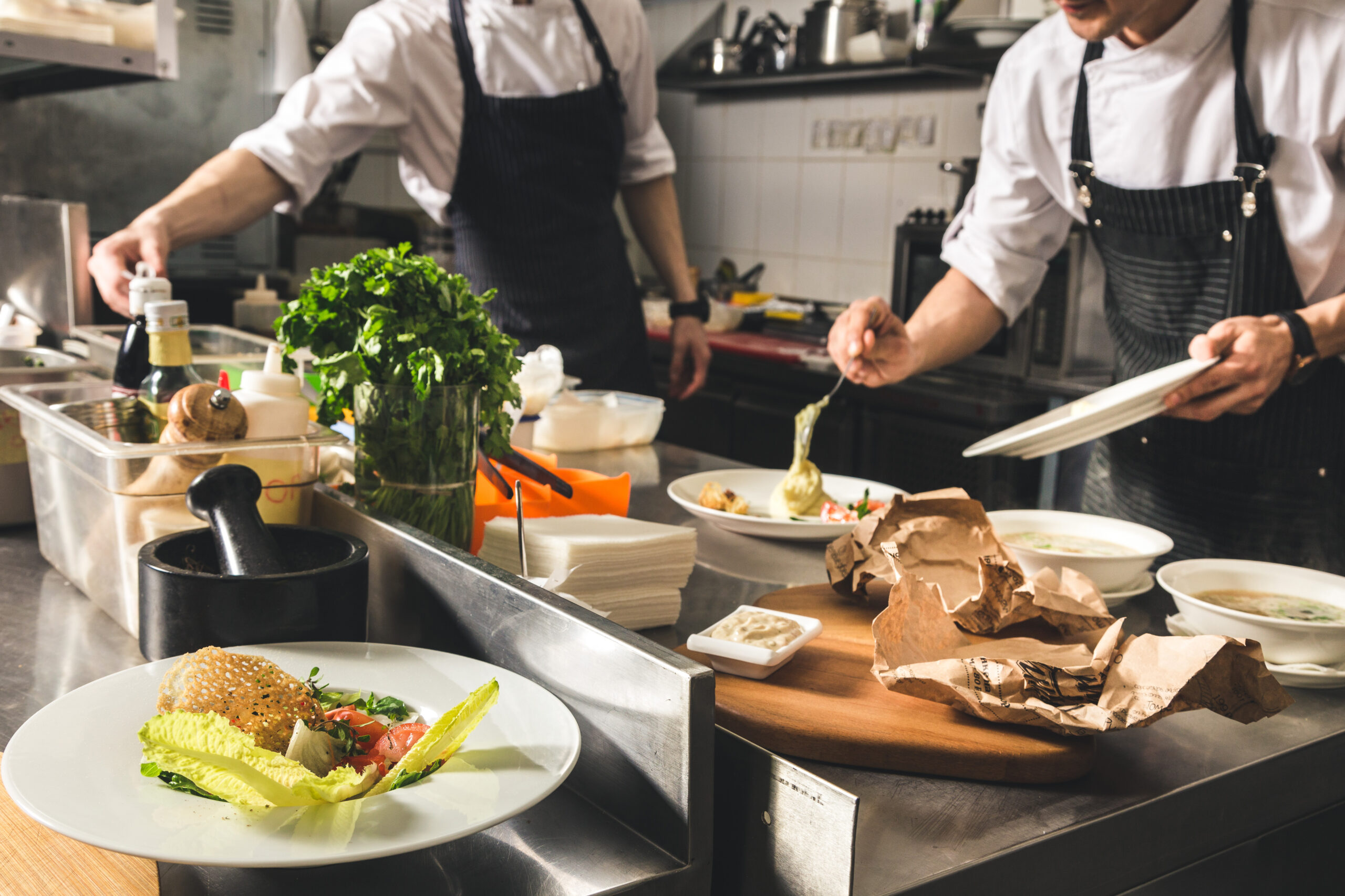 professional chef cooking in the kitchen restaurant at the hotel, preparing dinner. a cook in an apron makes a salad of vegetables and pizza.